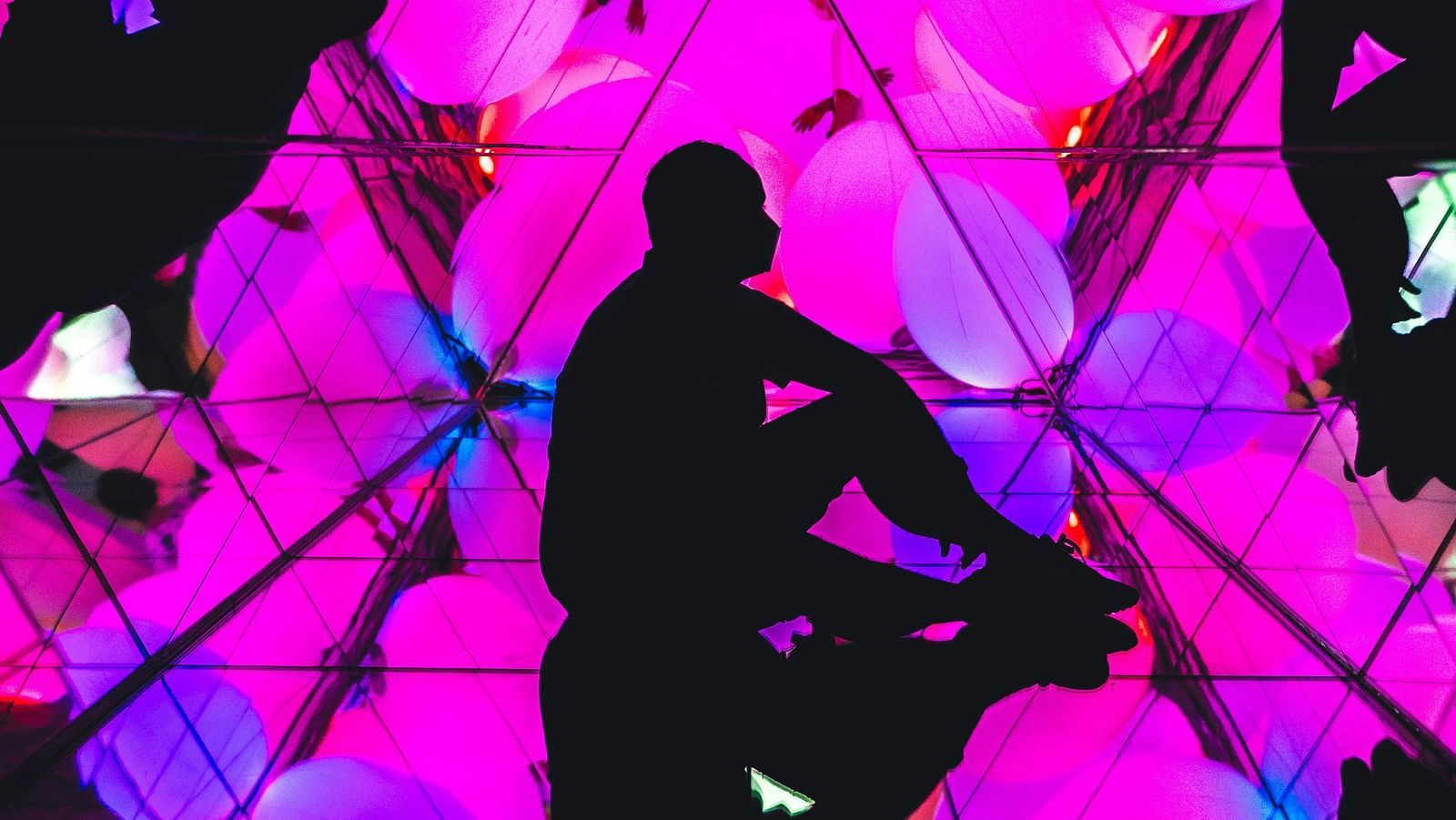 a person sitting on the floor of an interactive museum with abstract art on the wall and floor,