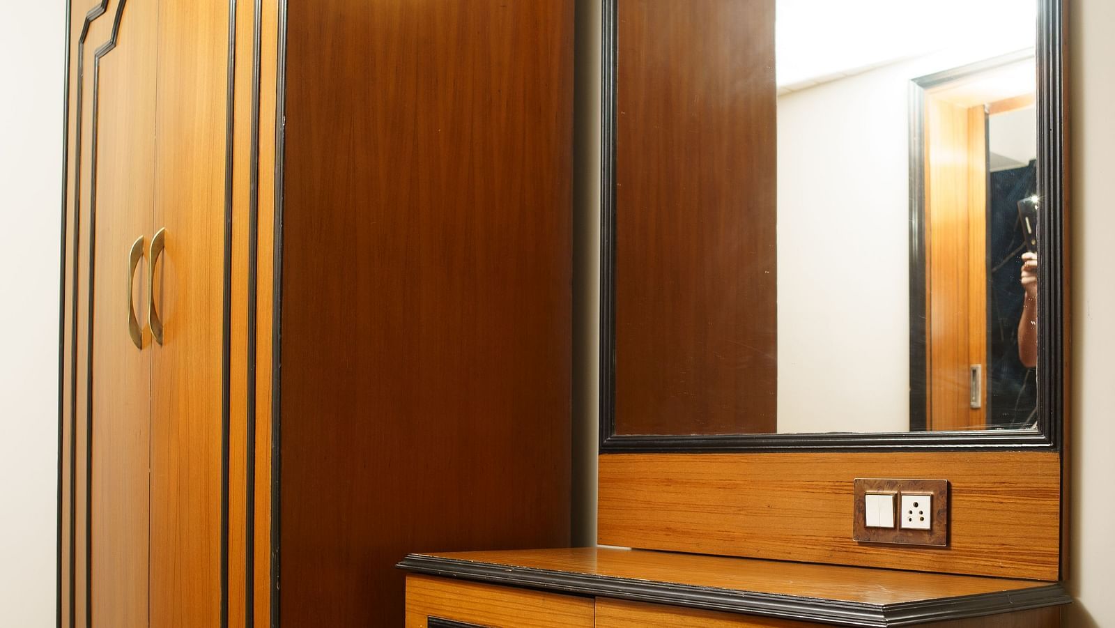 A wooden wardrobe next to a matching dressing table with drawers at Orsino Spa Resort.