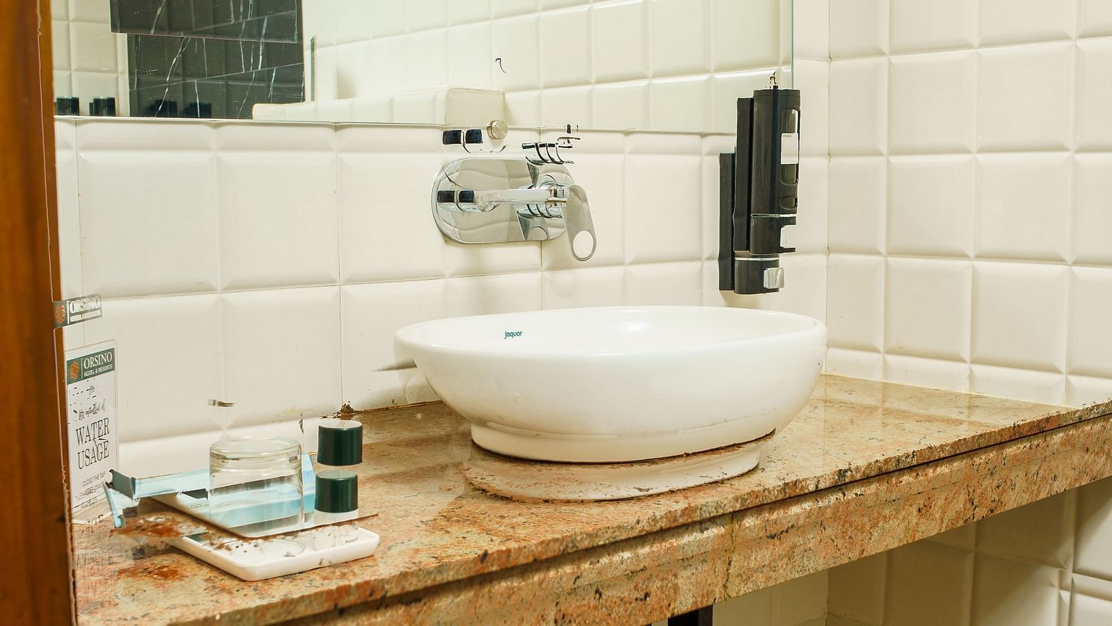 A bathroom with a white sink set into a wooden vanity unit, with a mirror and shelves below, at Orsino Spa Resort.