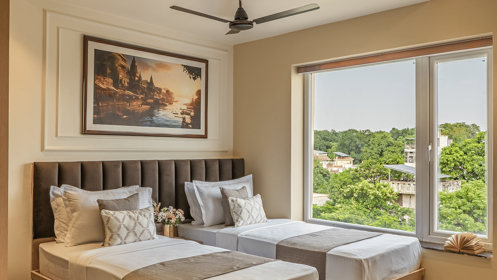 Twin Room at Perfectstayz Premium Lavender, Varanasi with 2 single beds, a brown padded headboard, a zebra print rug, a ghat painting, and a window with tree views.