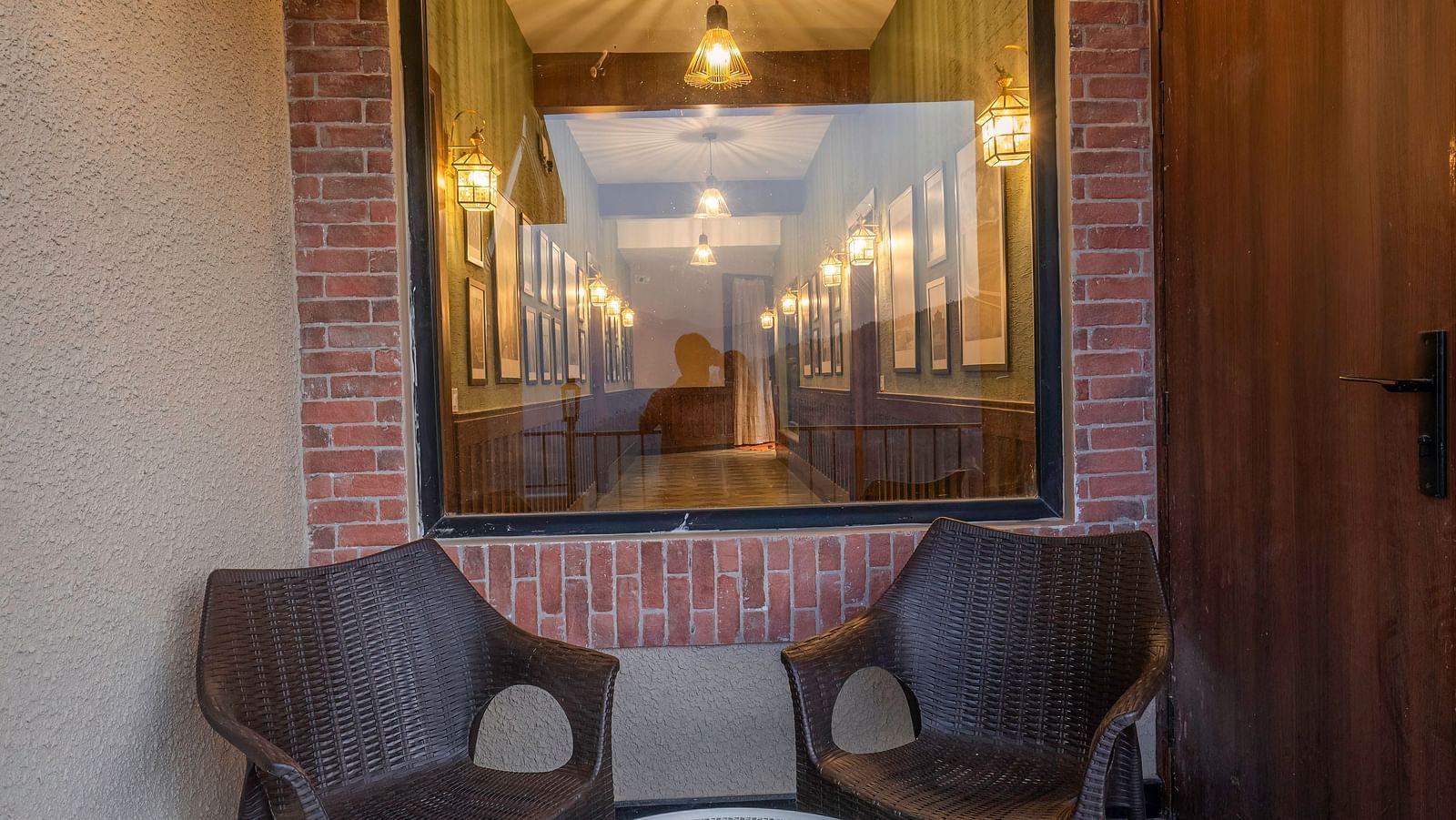 Cosy seating area with armchairs and a small round table in front, with warm lighting in the background at The Chamomile Estate.