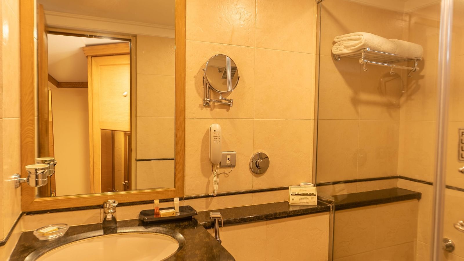 A view of the attached modern furnished bathroom with warm light at The President Hotel Jayanagar, Bangalore