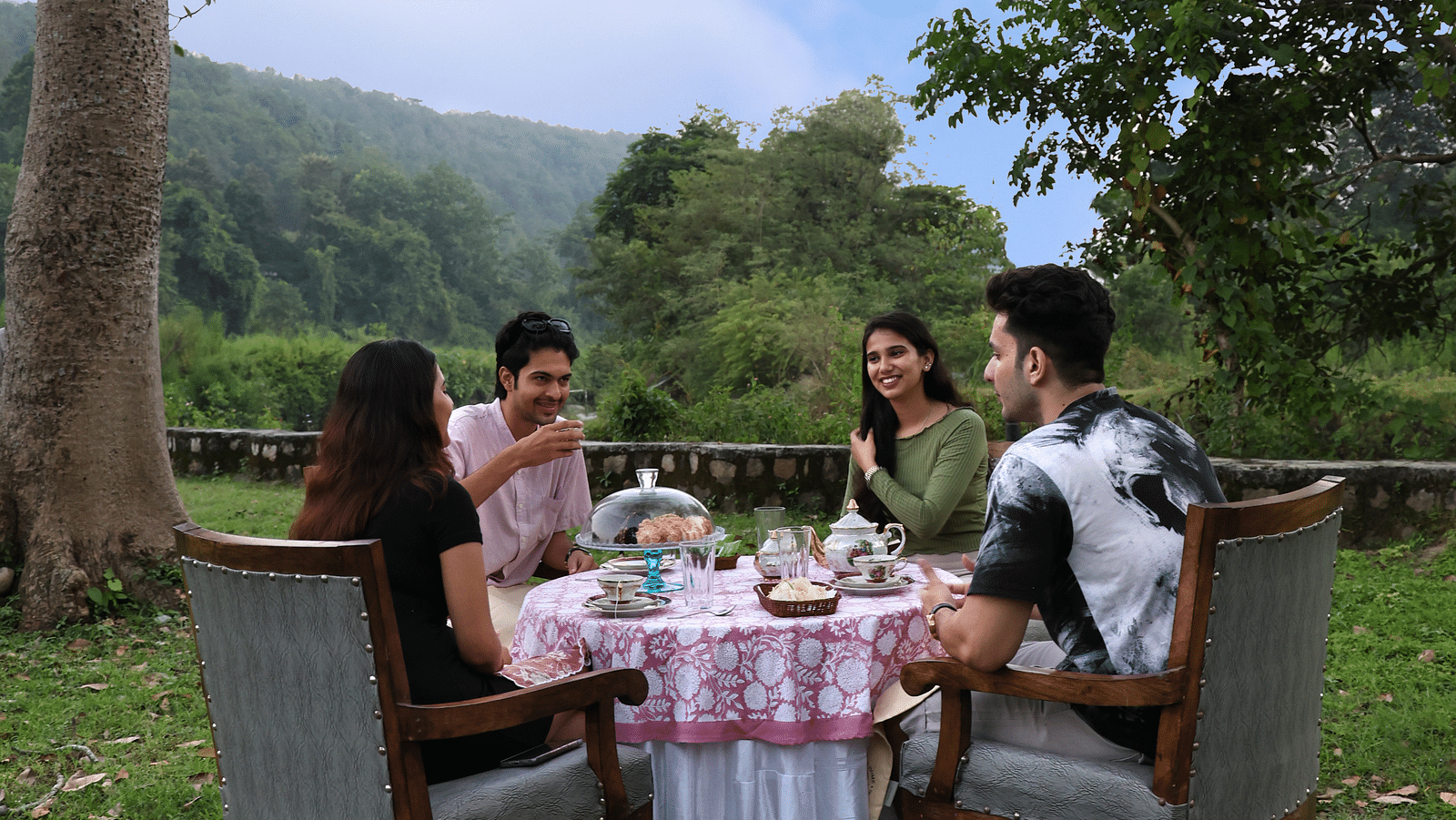 A lavish open-air dining setup with people enjoying a meal during the day at The Sylvan Retreat, Dehradun.