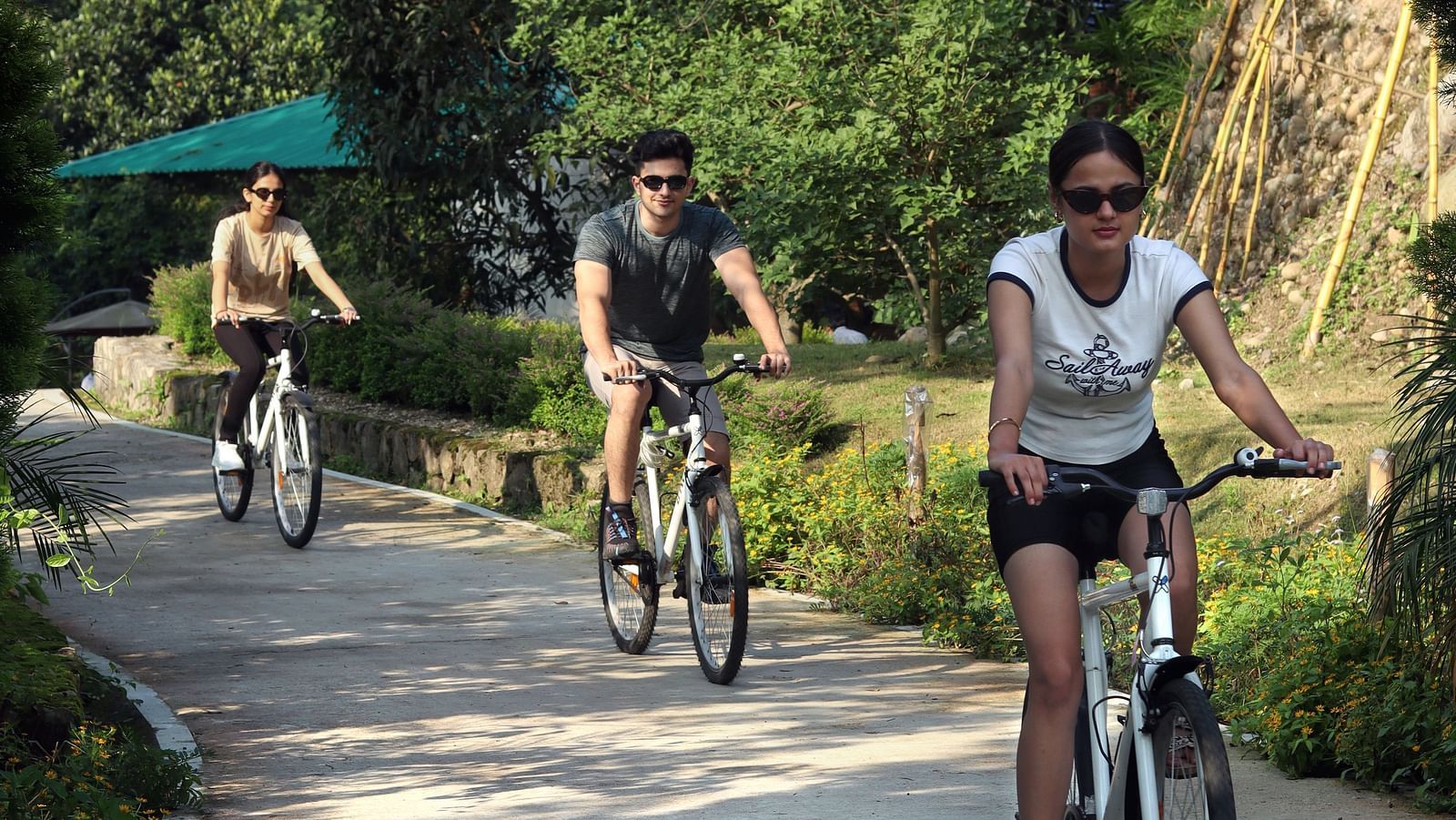 A group of people cycling on a pathway at A man flying a kite at The Sylvan Retreat, Dehradun.