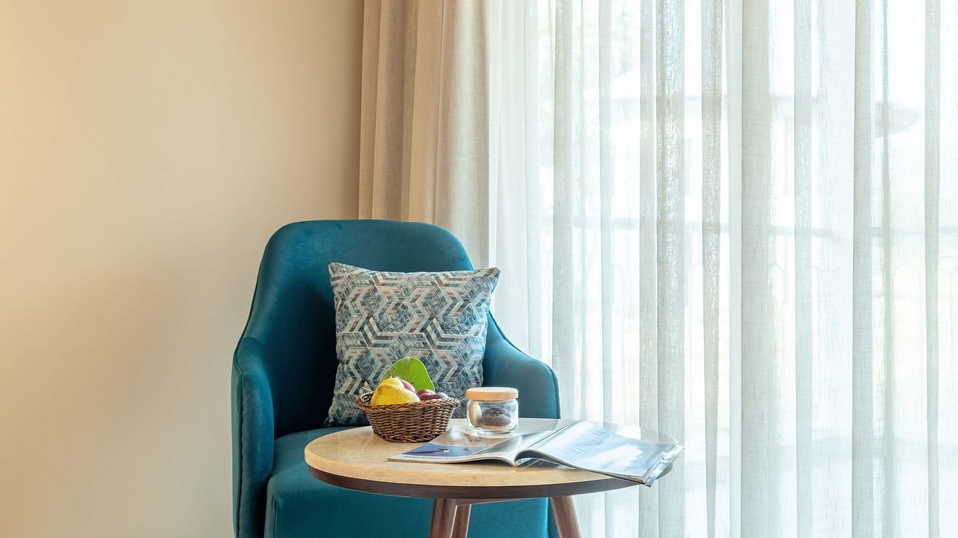 An image of a corner of a room near window where a sofa is placed along with tea table - Ananta Spa and Resort, Ajabgarh
