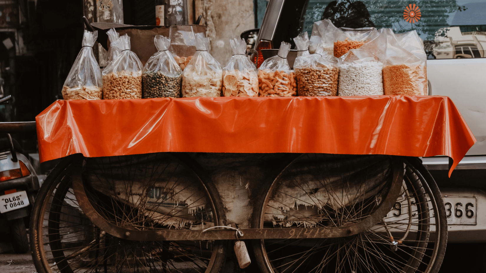 A street cart with metal wheels, with bags of spices and grains kept on a cloth