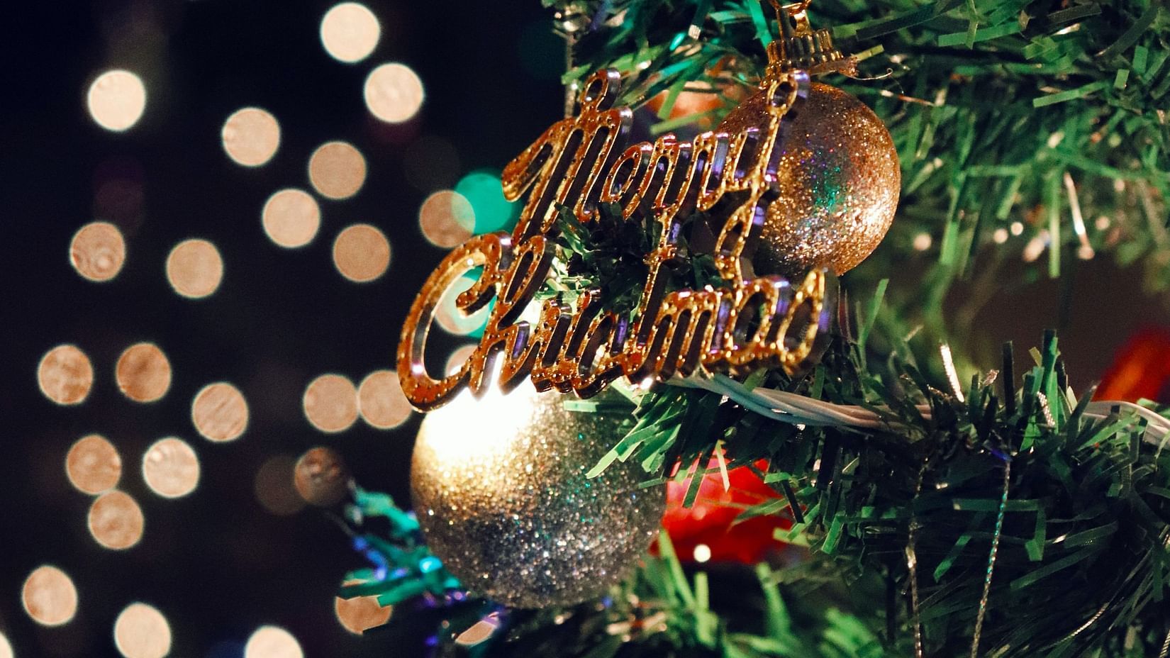 a christmas tree decorated with merry christmas ornament on it and other ornaments as well