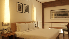 A bedroom with a king size bed, bedside tables, wall-mounted artwork, and wooden flooring in the Penthouse Suite at Clarks Amer, Jaipur, offers elegant Accommodation in Jaipur.