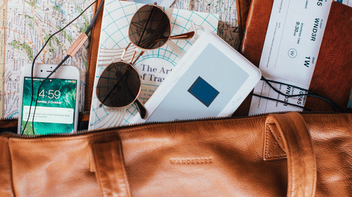 Picture of a brown leather tote bag with travel essentials
