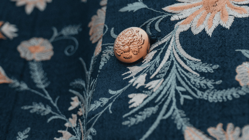 Close-up of embroidered floral fabric with decorative buttons.