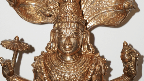 A detailed bronze statue of a Hindu deity with multiple arms and a cobra hood above its head is displayed.