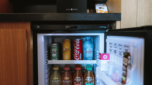 a small refrigerator inside a hotel room with drinks and snacks