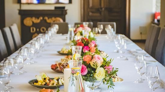 a long dining table in a room decorated with flowers and new glassware
