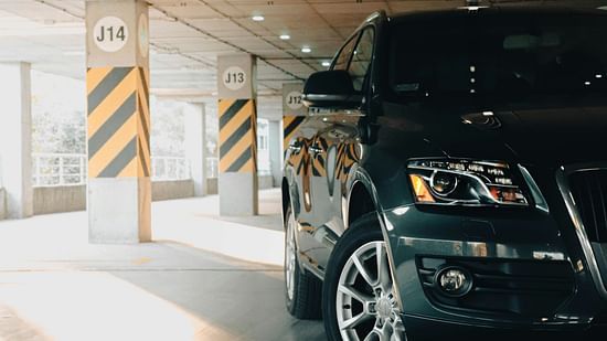 A front shot of a car beside pillars in the parking lot