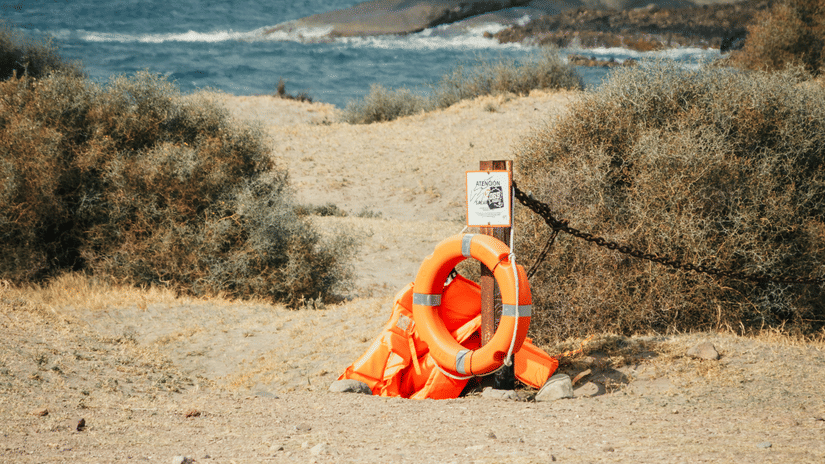 An overview of a beach with the ocean in the background and an orange coloured preserves placed on the beach.
