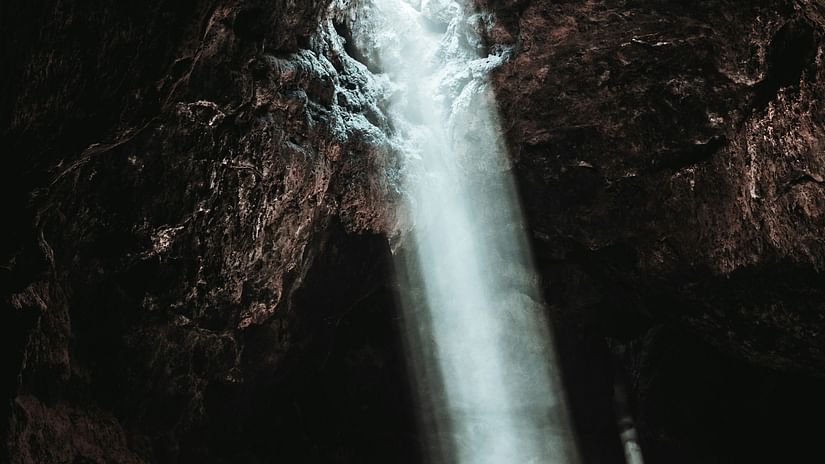 image of a cave with a beam of light coming from the roof of the cave