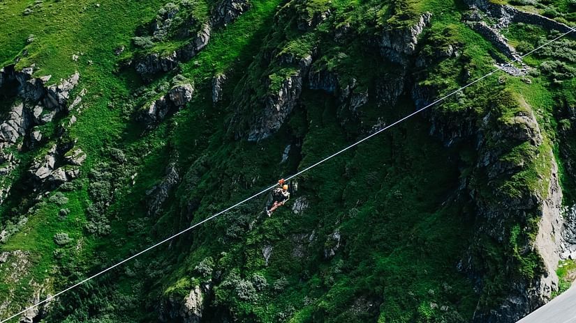 A view from above of a mountain with a person ziplining through it.