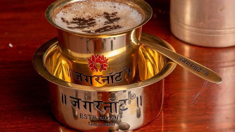 a filter coffee kept on a table with coffee beans littered next to it