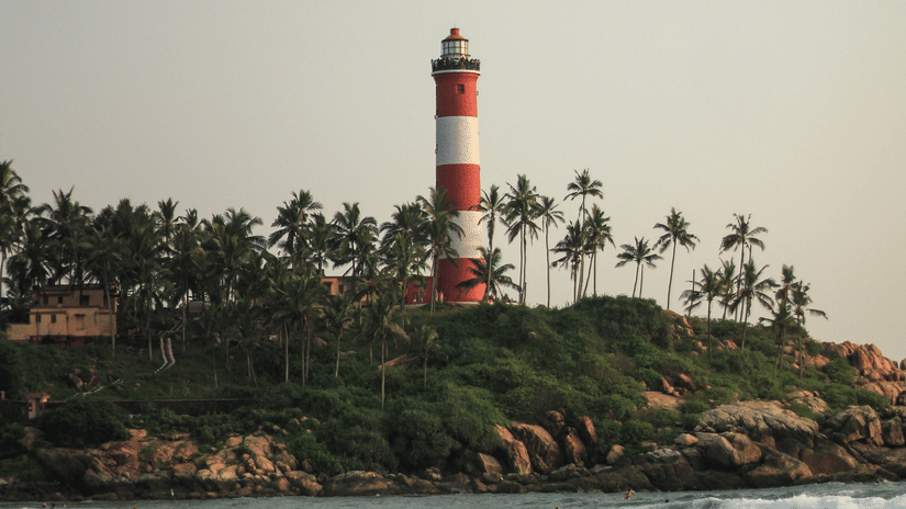 Kovalam Beach on a sunny day with waves crashing the shore where the lighthouse is