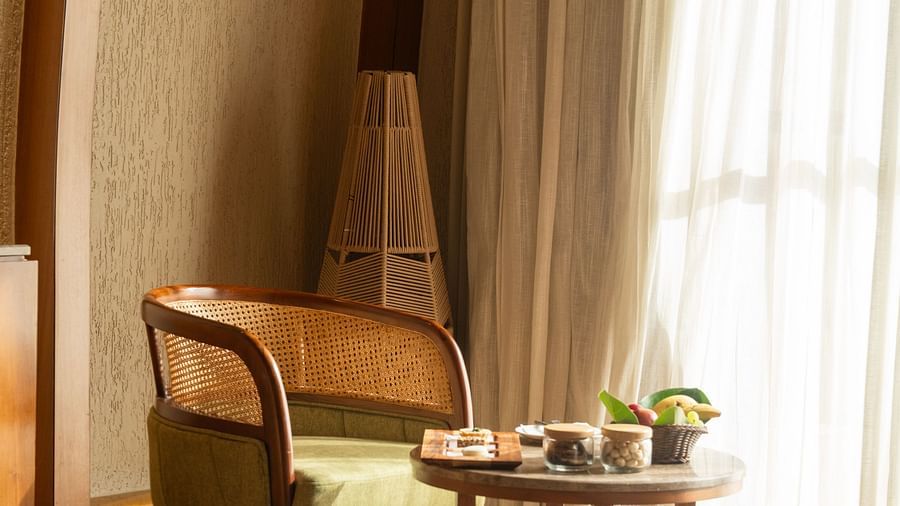 Warmly lit sitting area by the window, featuring wooden furniture and draped curtains at Ananta Spa and Resort, Ajabgarh.