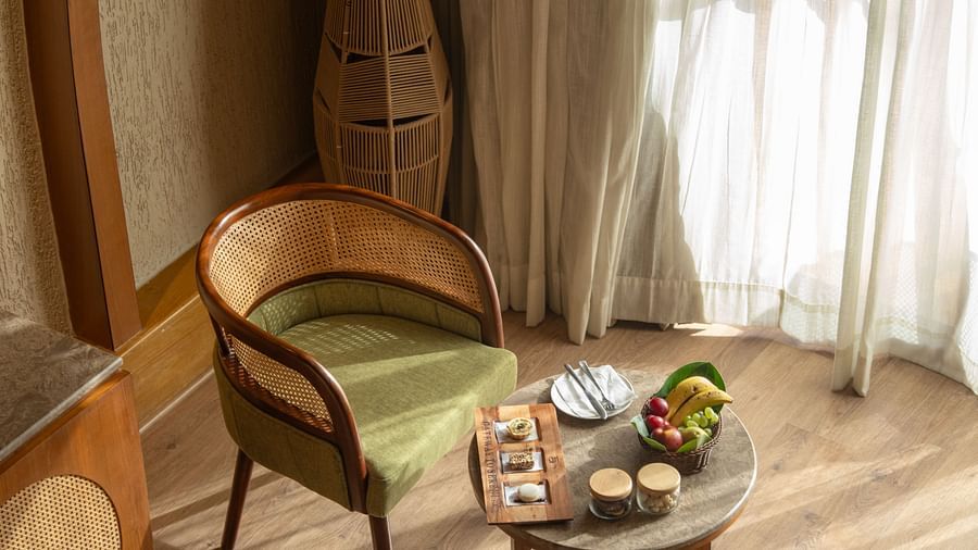 Seating arrangement with two chairs and a small table near a sunlit curtain at Ananta Spa and Resort, Ajabgarh.