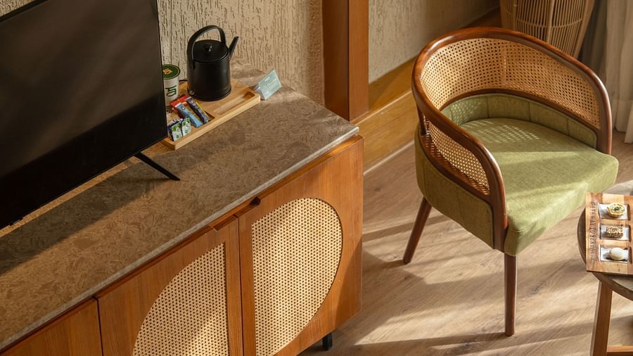 Flat-screen TV and writing desk setup next to a comfortable chair and cabinet at Ananta Spa and Resort, Ajabgarh.