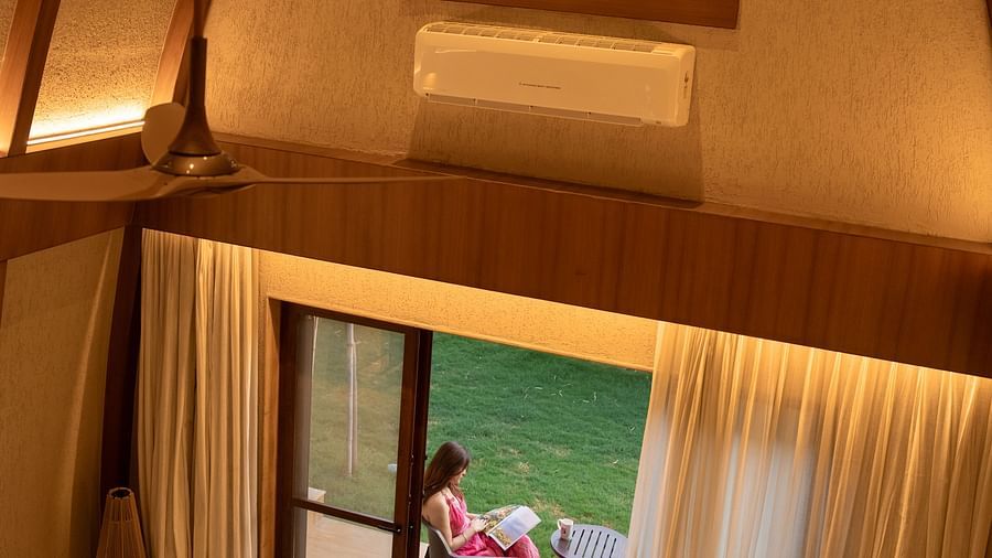 Room with high ceiling and arched window, opening to a patio with seating at Ananta Spa and Resort, Ajabgarh.