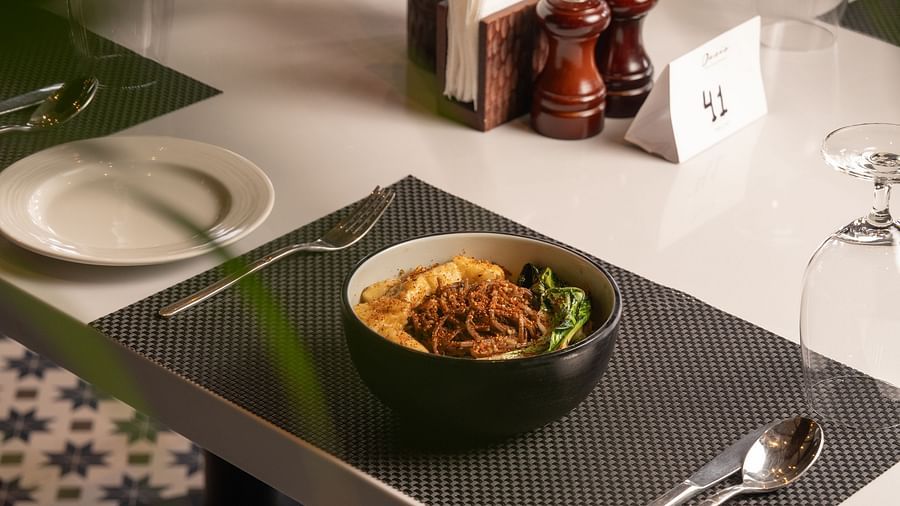 A bowl of curry placed on a table with silver cutlery nearby at Ananta Spa and Resort, Ajabgarh