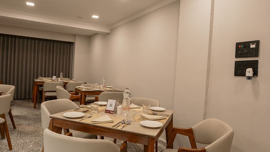 A neat dining area with a wooden table, chairs, and place settings - Biznotel By Pride Surat