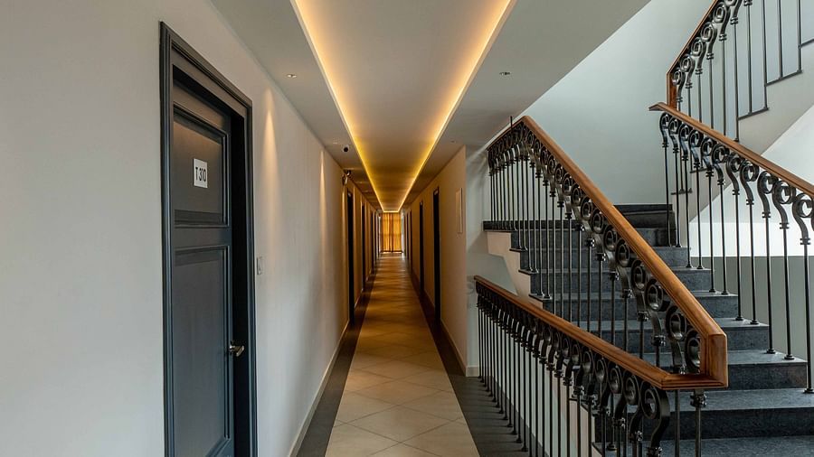 A brightly lit corridor leading to rooms and a staircase at our hotel - Court 11, Kochi