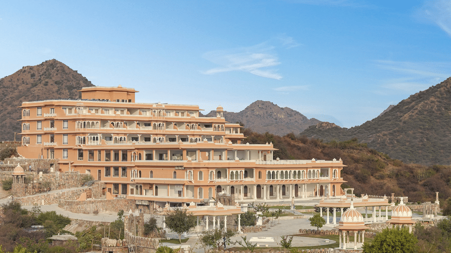 Location of Fateh Vilas by Fateh Collection with many trees in the foreground and mountains in the background