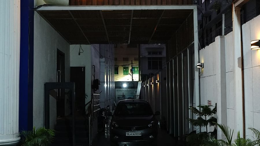 An image of a parking lot in Five Elements Hotels North Avenue, Delhi featuring a well lit name plate and below it there is a carport where a car is parked