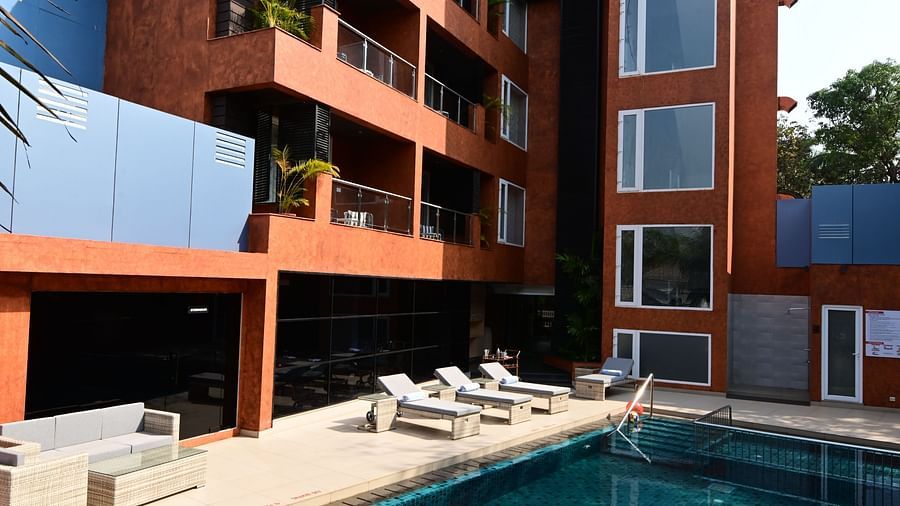 The outdoor swimming pool area with lounging chairs placed besides it at Golden Tulip Vagator, Goa