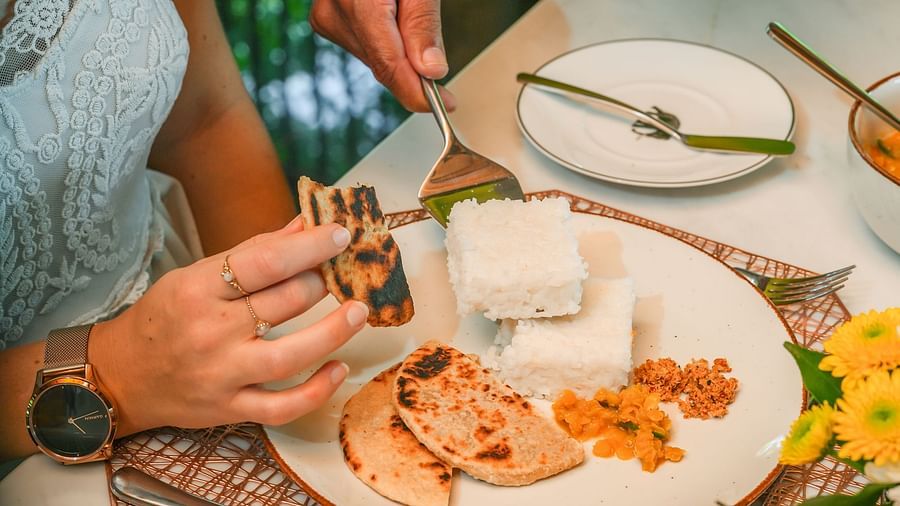 Close-up of a table with hands serving traditional dishes in a warm and inviting setting - Heavensa Villas and Suites by the Clarks, Galle