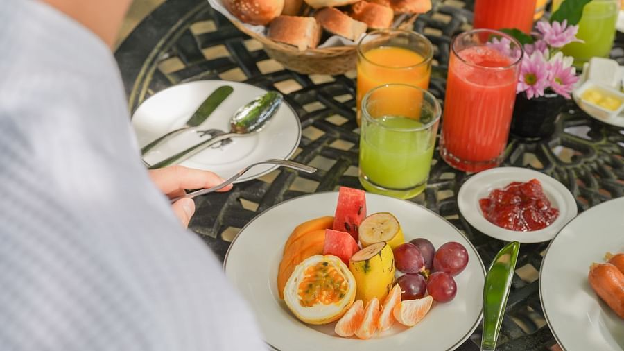 A close-up of a person enjoying a lavish breakfast spread with fresh juices, fruits, and traditional dishes - Heavensa Villas and Suites by the Clarks, Galle