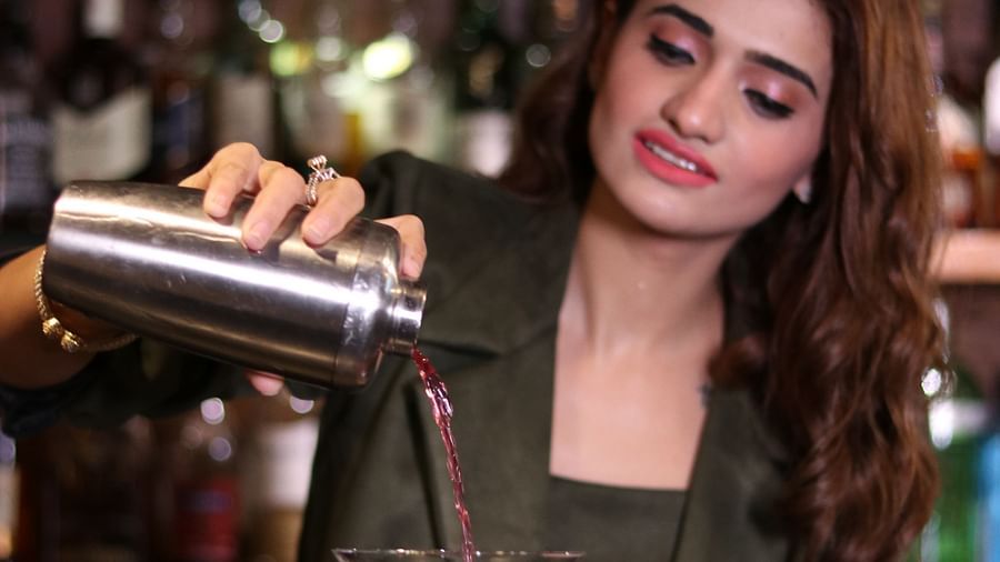 Heritage Village Manesar - image of a woman in a suit pouring a red coloured cocktain into a martini glass