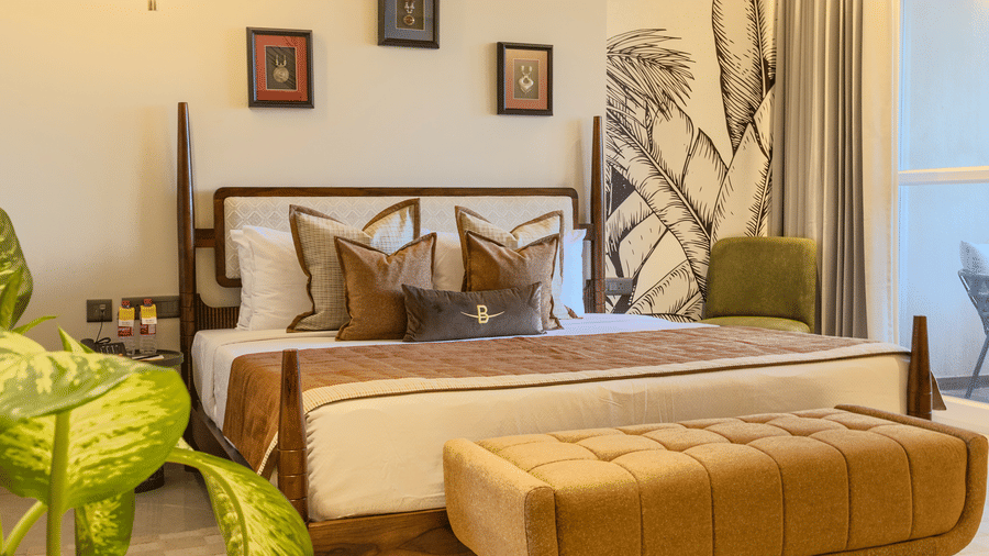 Neatly dressed bedroom with a cushioned bench at the foot of the bed and warm ambient lighting at Hotel Bawa, Udaipur