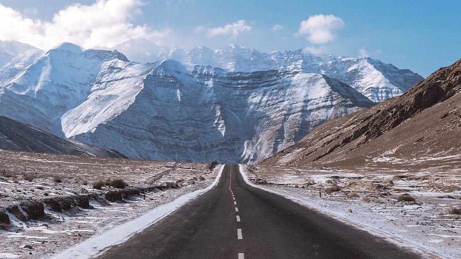 A view of a straight road leading towards majestic mountains.