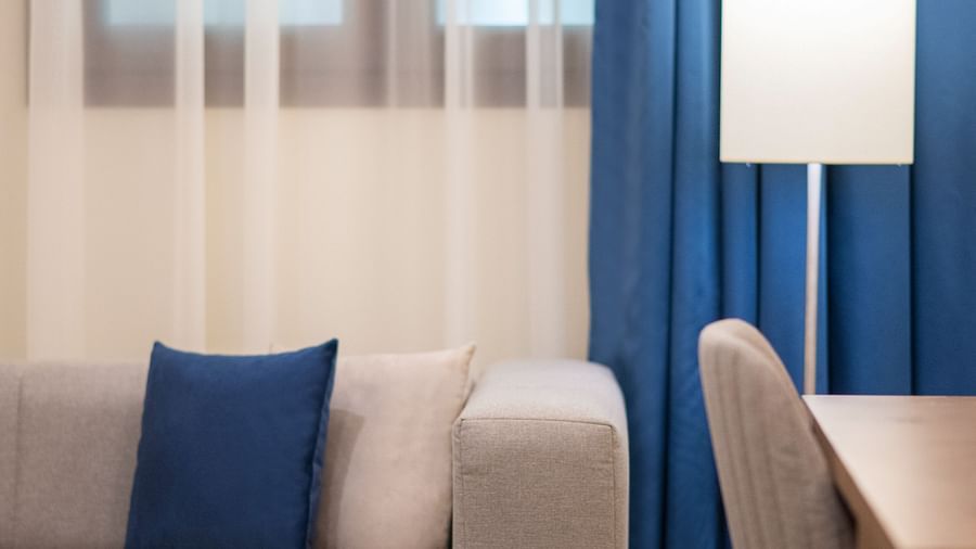 A close up shot of a sofa with a lamp next to it inside the Guest Room - La Maison Hotel, Doha