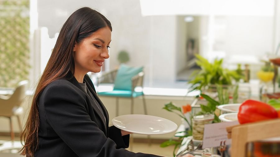 a woman helping herself to the food items in a Buffet at la patio - La Maison Hotel, Doha