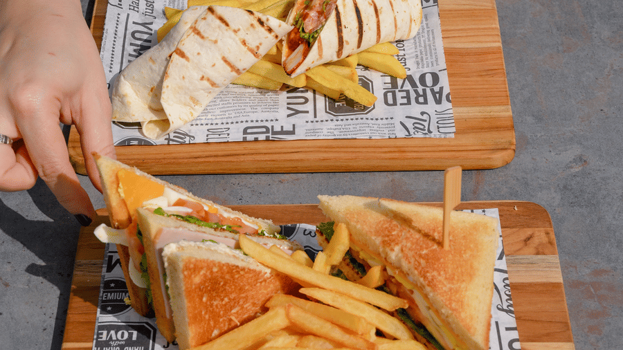Guest enjoying a burger and crispy chips served on wooden trays at La Maison Hotel, Doha.