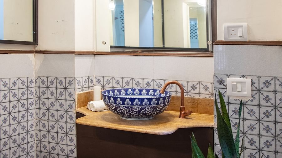 An image of a blue checked bathroom tiles with wooden colour basin  @ Lamrin Ucassaim Hotel, Goa