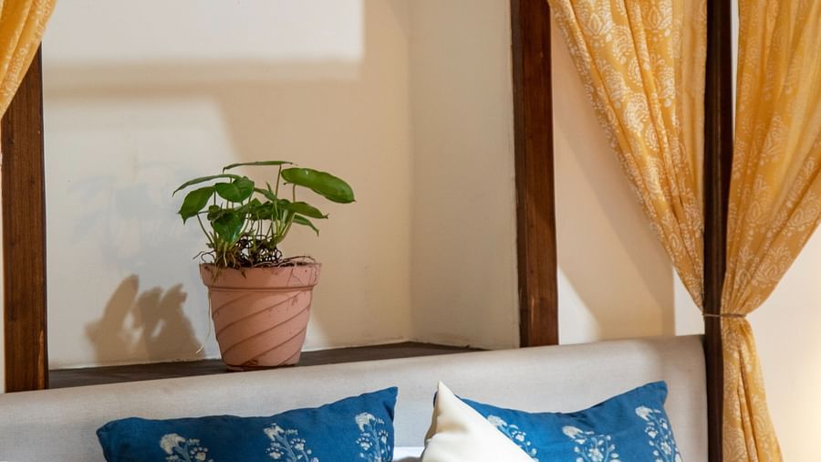 An image of a yellow canopy bed with blue pillows  at Lamrin Ucassaim Hotel, Goa