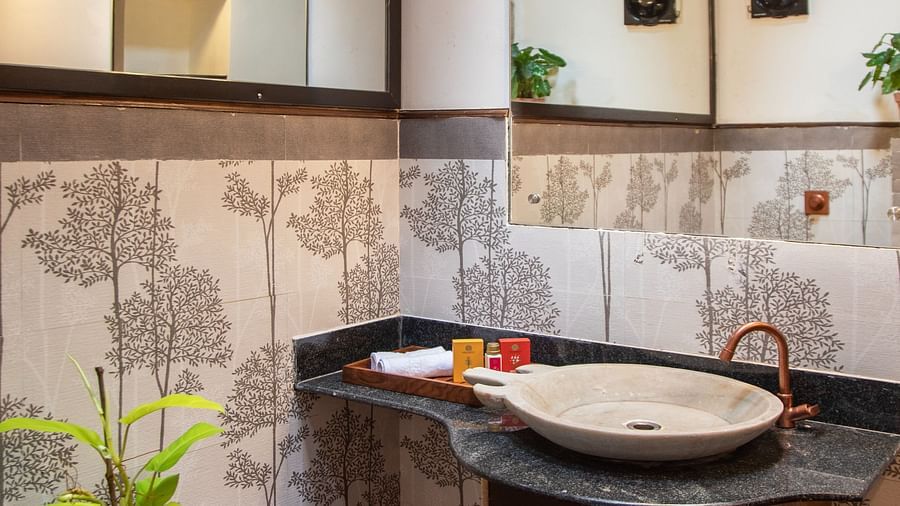 bathroom with tiled walls and green plants @ Lamrin Ucassaim Hotel, Goa