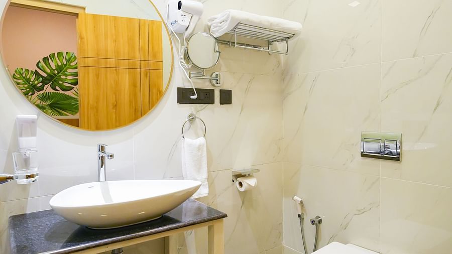 Image of bathroom featuring a circular mirror mounted on wall over a fancy sink and a toilet next to it