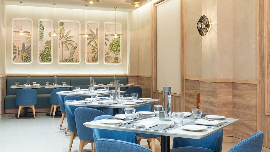 A restaurant dining area with blue upholstered chairs and a modern chandelier.
