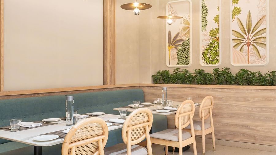 A restaurant interior with a long dining table and a plant wall.