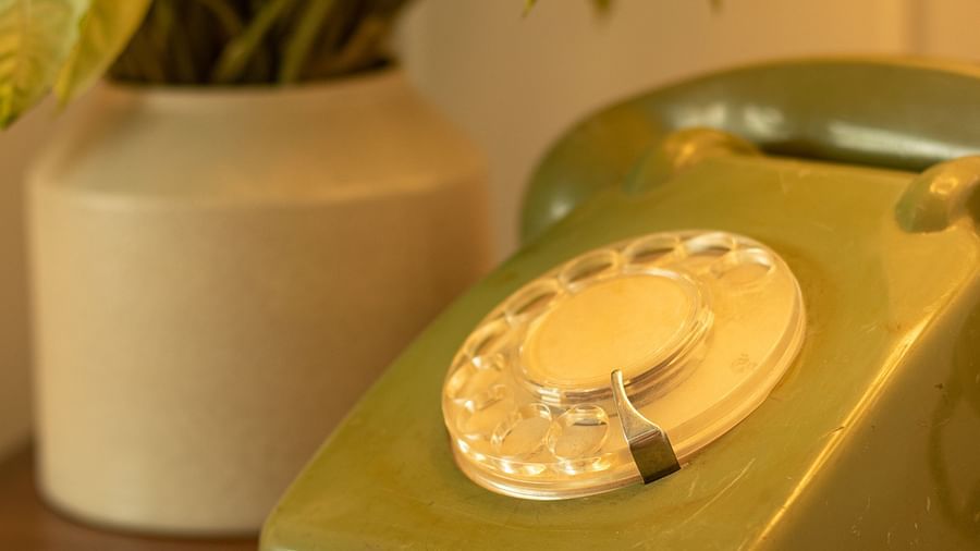 an old-fashioned telephone kept on a table next to a vase - polo floatel kolkata