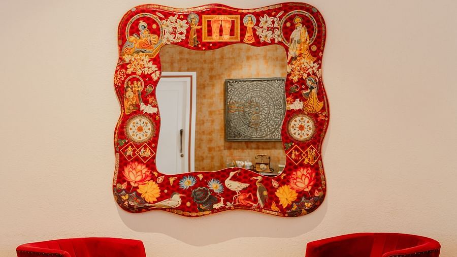Ornate mirror and red velvet chairs in a cozy living room.