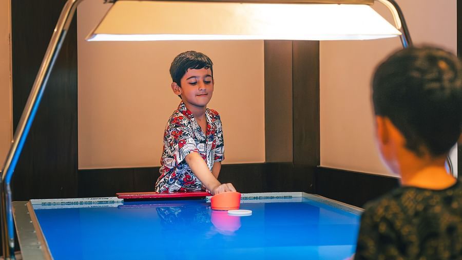 Two kids playing an indoor game on a blue table Image at The Ananta Udaipur